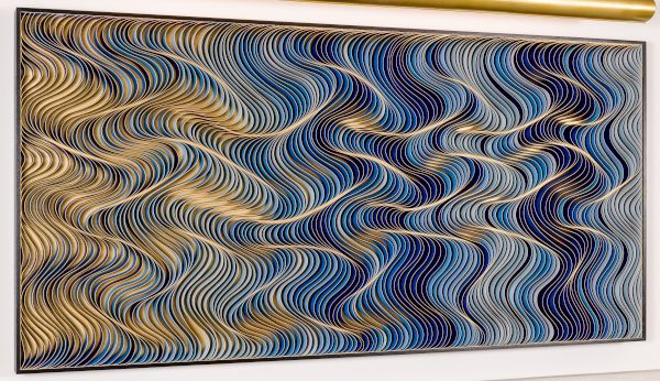 An abstract wall piece with swirling, wavy blue, gold, and cream lines forming a hypnotic, checker-like pattern across the frame.