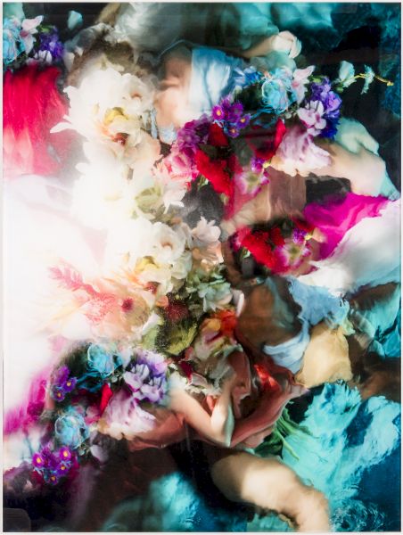 Colorful, abstract collage of flowers and blurred faces blending together; vibrant reds, blues, purples with a bright light wash at left end.