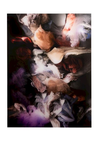 A close-up of swirling, abstract paint textures and soft fabric-like shapes in dark tones, with streaks of warm peach, white, and purple, artistic chaos.